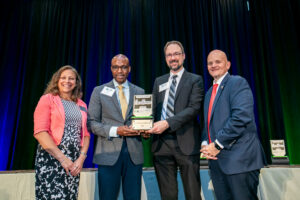 Four people standing together on stage accepting award